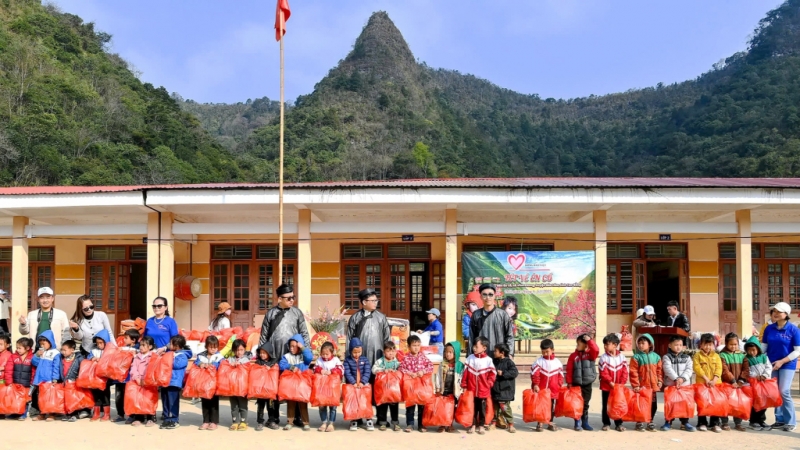 Các thành viên đoàn thiện nguyện trao quà (đồng phục, quần áo ấm, ba lô, mũ, ủng...) cho 157 học sinh ở Điểm trường Én Cổ.